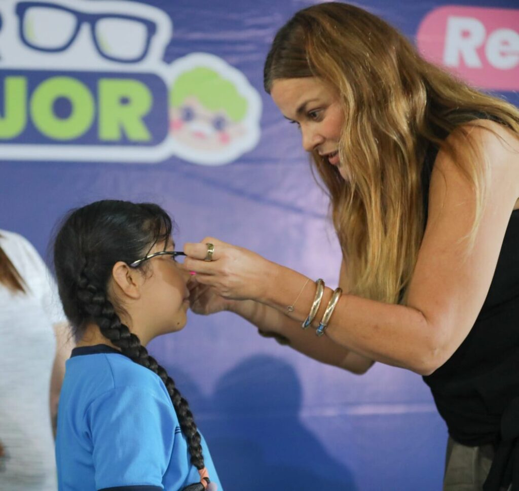 La alcaldesa Cecilia Patrón colocando unos lentes nuevos a un niño sonriente
