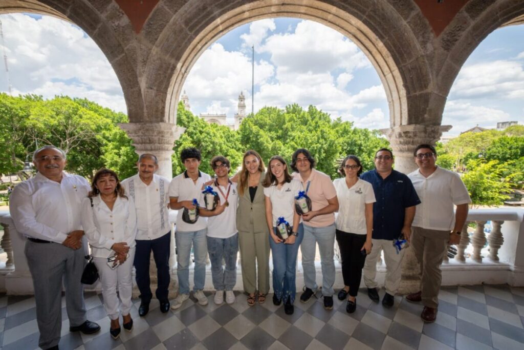 Cecilia Patrón sonriendo junto a los tres jóvenes medallistas de la olimpiada